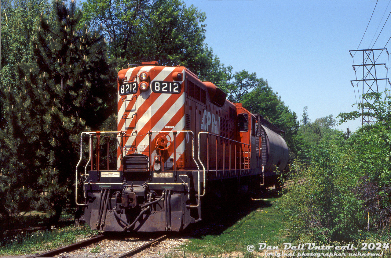 "Come to Marineland, where you can touch a whale in Friendship Cove, see the dolphins do their dolphin thing, and...shoot a train too?". Why yes!

CP Rail GP9u 8212 handles a single covered hopper inside Marineland, sitting by the switch to the Washington Mills siding at the main access road inside the amusement park grounds. This short local is working the CP Chippawa Industrial Spur (around Mile 13.50) that runs south from CP's Hamilton Sub (the old PC/CR Canada Division line, aka the CASO, and now CP's Montrose Spur) from the end-of-track around Clifton Hill down to the Welland River in Chippawa, where the line ends by the only other customer, Saint Gobain. A 1992 CP timetable specifically states only single unit operation is permitted on the entire spur, with a speed restriction of maximum 5 mph. The date of this blank, unlabeled slide is unknown, but judging by other photos of 8212 it was taken sometime in the 1990's.

Since Marineland is private property, gates block off this portion of the rail line through the park at both ends. Access here for a photo or two would have only been possible by paying admission to Marineland to get into the park (Marineland was the latecomer, having been built in the early 1960's along one side of the line, but it looks like they only began to expanded their park to the property across the tracks in the 1970's-80s).

This was once the old Michigan Central Niagara Branch that ran from Fort Erie to Niagara-on-the-Lake. Research shows the line south of Chippawa was abandoned in 1941, and the line then served as a short spur from there to the mainline to access a few local customers. The line passed through New York Central, Penn Central and Conrail ownership until CP acquired the old CASO from Conrail in the 1980's. When the main CASO line (CP Hamilton Sub) through the downtown Niagara Falls tourist area was lifted in 2001, it was removed only as far south as the switch to the Chippawa Industrial Spur, letting CP locals continue to have access to serve Washington Mills and Saint Gobain.

With all the controversy surrounding Marineland and its recent change of ownership, it should be interesting to see what becomes of the place and how this line fairs in the future.

Original photographer unknown, Dan Dell'Unto collection slide.