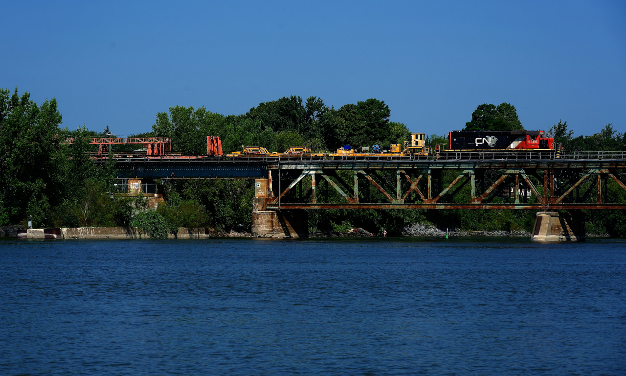 Rail train CN 907 has CN 5386 for power as it crosses the Richelieu River at Otterburn Park. It is lifting rail on the St-Hyacinthe Sub.