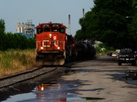 CN YRP002 is leaving Bitumar with eight cars as it parallels a quiet street.