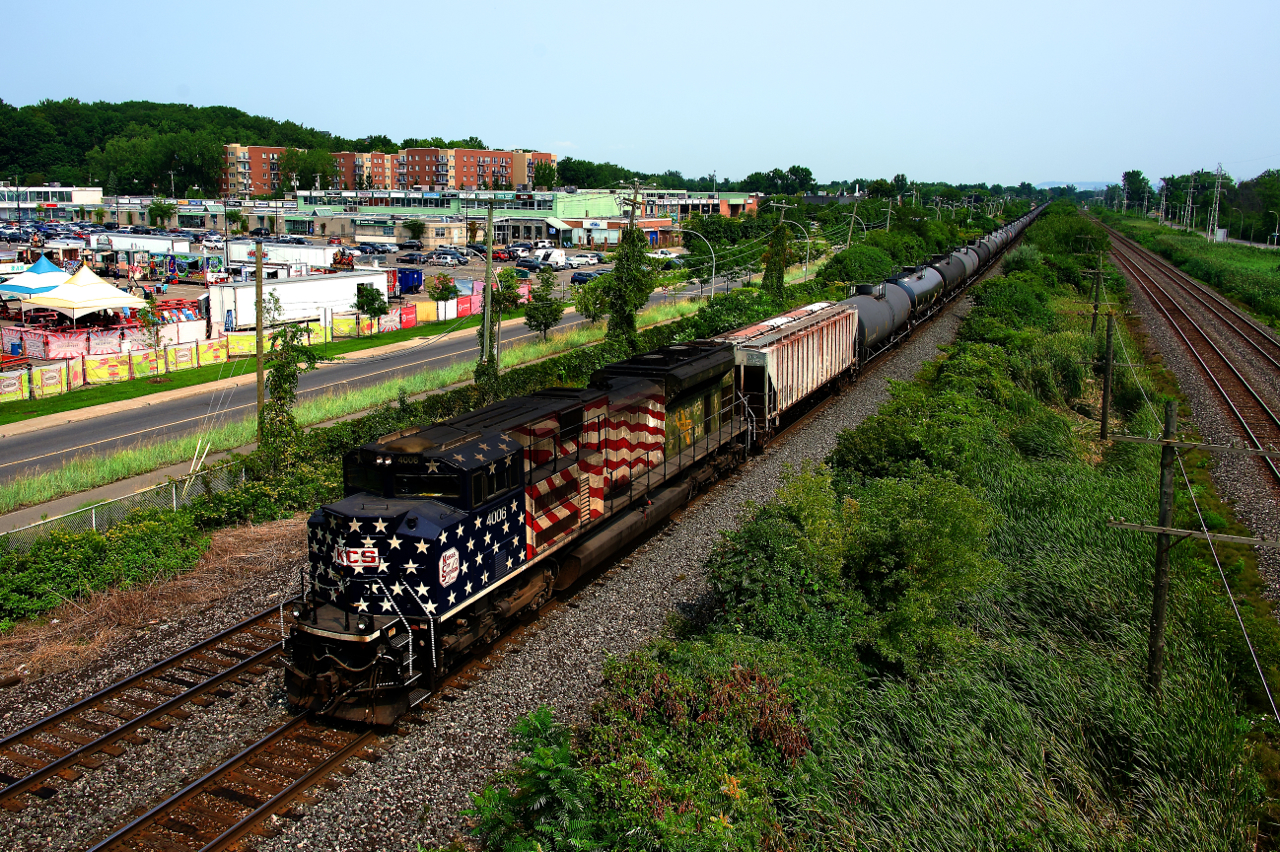 CPKC 528 with rear DPU KCS 4006 is passing a poutine festival on a smokey afternoon.