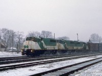 CP train #904 heads eastbound through the falling snow, passing the station and yard at Galt. Leading are a trio of borrowed GO Transit commuter locomotives, GP40-2W's 702, 700 and GP40-3 722. It's a Saturday, so this power was likely borrowed (from Guelph Junction?) to run weekend freight service on CP before being returned in time for their Monday morning commuter duties. GO would soon start receiving the first of their new F59PH locomotives from GMD, which would eventually render the whole GP40 and F40 fleet surplus.
<br><br>
<i>Bill McArthur photo, Dan Dell'Unto collection slide.</i>