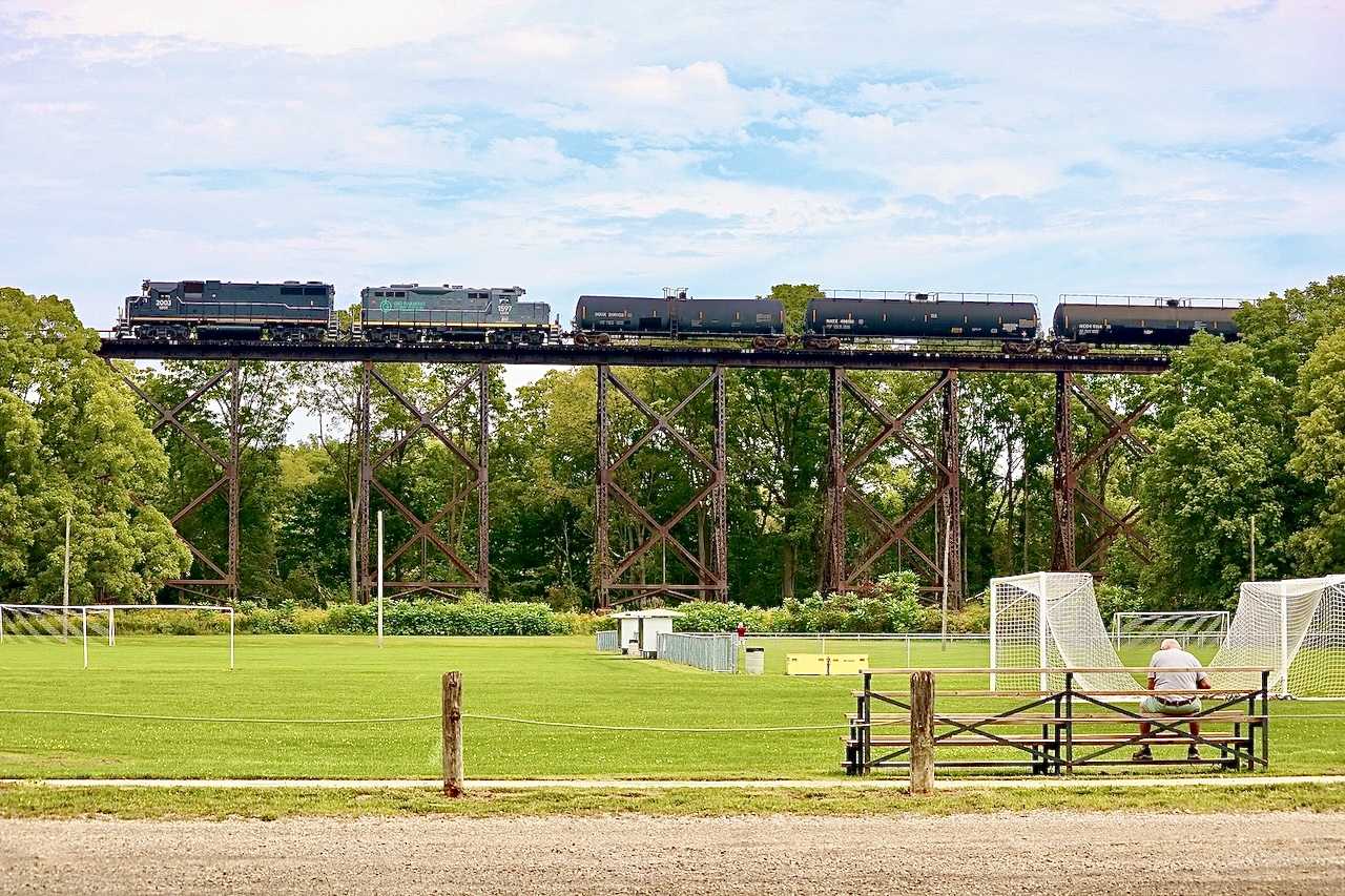 Field of dreams. I have to admit I’d have a problem staying focused playing soccer here, LOL. Years ago not just CN, but NS and its predecessors plied these rails. I’ve shot a few trains on this bridge over the years but this is the first time I have caught Gio Rail here. It’s unfortunately the Ford plant west of here is long gone as it provided several daily opportunities to photograph trains here. Today most trains caught on the bridge are simply using it for head room while they work the small CN yard to the east. Here LDS leased GP38 2003 and GP9U 1597 work their GIO Rail train  of solid tank cars before lifting 3 cars and heading back east.