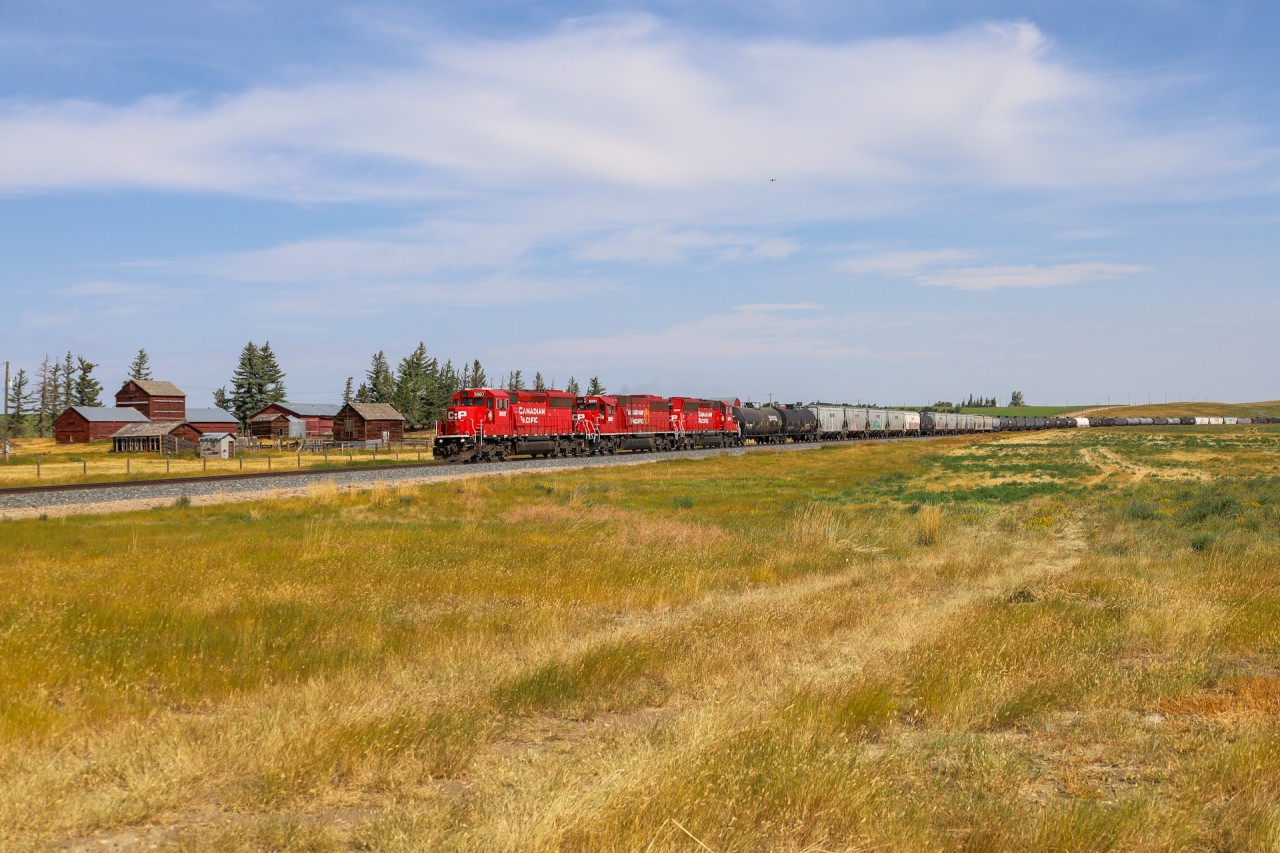 CPKC B08-30 cruises into Milk River, Alberta, passing an old homestead beside the Montana Sub.