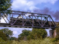 An Upper Canada Railway Society excursion behind CNR U-2-e 6167 is seen along the Fergus sub at Drayton, rumbling over the Conestogo River bridge. The train, carrying over 500 passengers, travelled from Toronto - Dundas - Lynden - Guelph - Palmerston - Stratford - Kitchener - Georgetown - Toronto.

<br><br><i>Scan and editing by Jacob Patterson.</i>