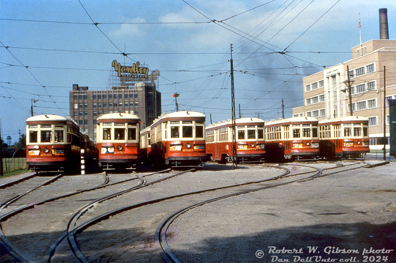 Toronto Transit Commission 2546, 2950, 2920, 2972, 2974, and 2958 are just some of the early 1920's Peter Witt streetcars stored in the TTC's temporary Harbour Yard on the harbourfront in downtown Toronto. These particular cars were "trailer train" consists with a "Large Witt" that hauled an unpowered trailer Witt, the extra capacity necessary for operation on the busy Yonge route between downtown and Glen Echo Loop.

Storage here was necessary due to construction of the new Yonge subway line's terminal facilities at Eglinton & Yonge, that interfering with streetcar storage and operation at the TTC's existing Eglinton Carhouse. The lack of space at Eglinton forced the TTC to store and operate its Yonge streetcars from this temporary 6-track yard, built on Toronto Harbour Commission lands at the south end of the busy Yonge streetcar route.

This lasted a few years (1951-1954) until subway construction was finished and the Yonge streetcar route was replaced with the new Yonge subway line (opened in March of the next year). Overnight, a lot of the old Peter Witt fleet suddenly became surplus, and they were rounded up and stored at Harbour Yard awaiting disposal for scrap or resale, including all of the trailers. After dispostal, the temporary yard was removed.

Newer more modern PCC streetcars handled most of Toronto's streetcar route demands going forward, but a handful of Peter Witt streetcars remained in service until the University subway line opened in 1963, and a final few saw limited use but were kept around until retirement in 1965.

The temporary TTC Harbour Yard was located on the parcel of THC land bordered by Harbour Street, Bay Street, York Street and Queen's Quay. Yardley's Perfumes is visible in the background along York (it had a rail siding from nearby Rees St. Yard). On the right is the brand new Workmen's Compensation Board Building at 90 Harbour Street (built 1953, demolished 2011). Downtown condos and modern office towers (and "Love Park") reside on the land here today.

Robert W. Gibson photo, Dan Dell'Unto collecton slide.