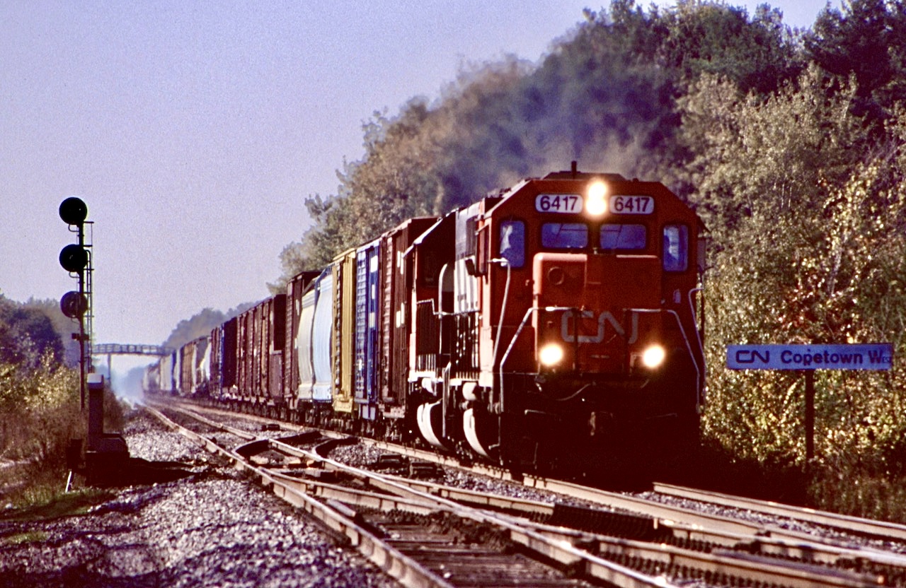 Former DT&I 417, repainted into CN/GTW 6417 still shows the crude plate job on its nose used to cover its former bell location from when it was built. Today the veteran GP40 works for RJ Corman, but back in 1997 it still plied CN rails as seen here heading eastbound under some not so great back lit conditions at Copetown West.