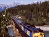 West of Edmonton, CN utilizes portions of Canadian Northern and Grand Trunk Pacific lines dating from the nineteen-teens railway construction mania that led to Canadian National being created.  West of Entrance, CN crossed the Athabasca River on a new (1926) alignment diverging from the GTP route around today’s mileage 190.8 to join the Canadian Northern route on the north side, with the CNoR route visible in this 1987-05-25 view of VIA No. 4 as the road to the right from the third passenger car.

<p>Behind this train are stations Solomon and next Swan Landing, junction with the Alberta Resources Railway north to Grande Prairie.