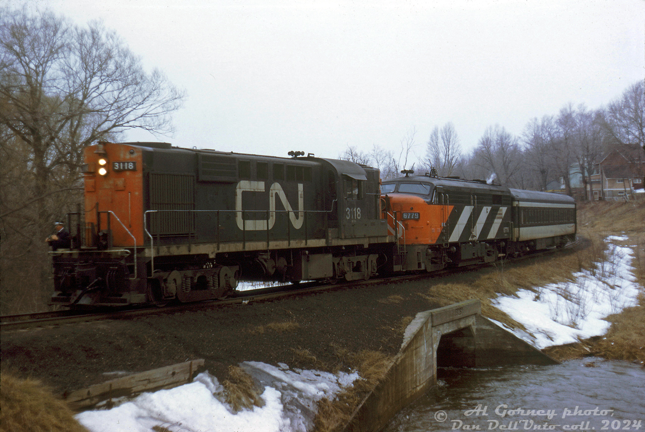 CN RS18 3118, FPA4 6779 and a single passenger car work their way back to the station on the Brockville Loop Line after visiting the Brockville wye (located amid a residential area to the southwest of the CN station area). After some research and input from others train appears to be heading eastbound on the north end of the Brockville Loop Line, crossing over a culvert for Butler's Creek and approaching Perth Street crossing. The houses in the background appear to be along Hubbell Street.The wye trackage was part of the old Brockville, Westport & North-Western Railway, that ran between Brockville and Westport, Ontario. The line was acquired by Canadian Northern, and became part of Canadian National, who abandoned it in 1952. The wye and CN connecting track (the "Brockville Loop Line" that ran from the CN station area west, ducking under the Kingston Sub to get to the wye and BW&NW) was left intact, and used by CN and later VIA to wye passenger power and equipment as needed into at least the mid-80's. The wye and line is now part of the Brock Trail.Al Gorney photo, Dan Dell'Unto collection slide.