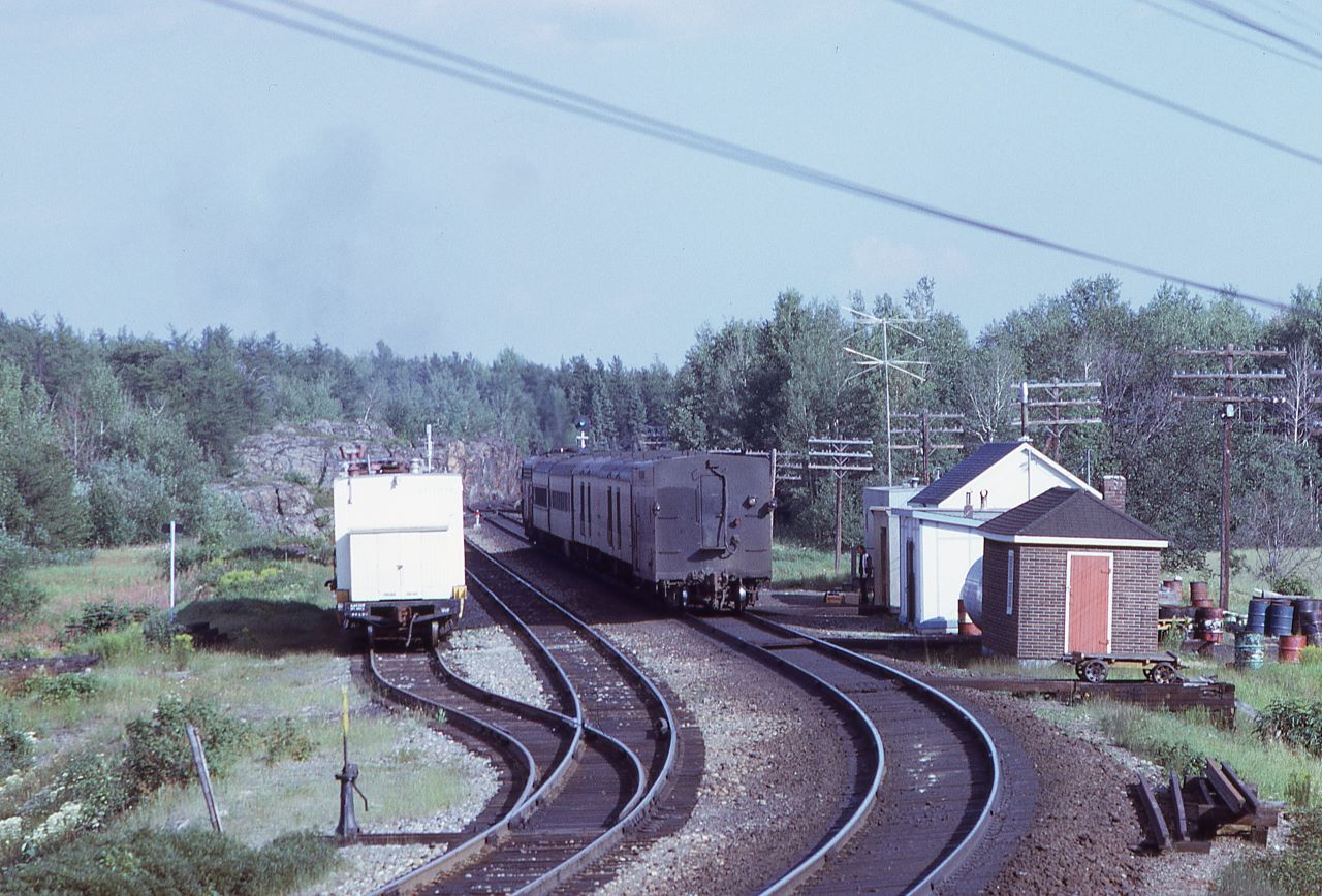 After meeting a westbound freight and making its station stop, CN train 676 with 6526 for power and steam generator car 15450 wearing the markers accelerates away from Laforest.  The clear signal at the east end of Laforest is clearly evident.  Lots of 1970ish railroad detail is evident in the photo including a work train in the back track.

A view of train 676 approaching can be viewed here: www.railpictures.ca/?attachment_id=45136