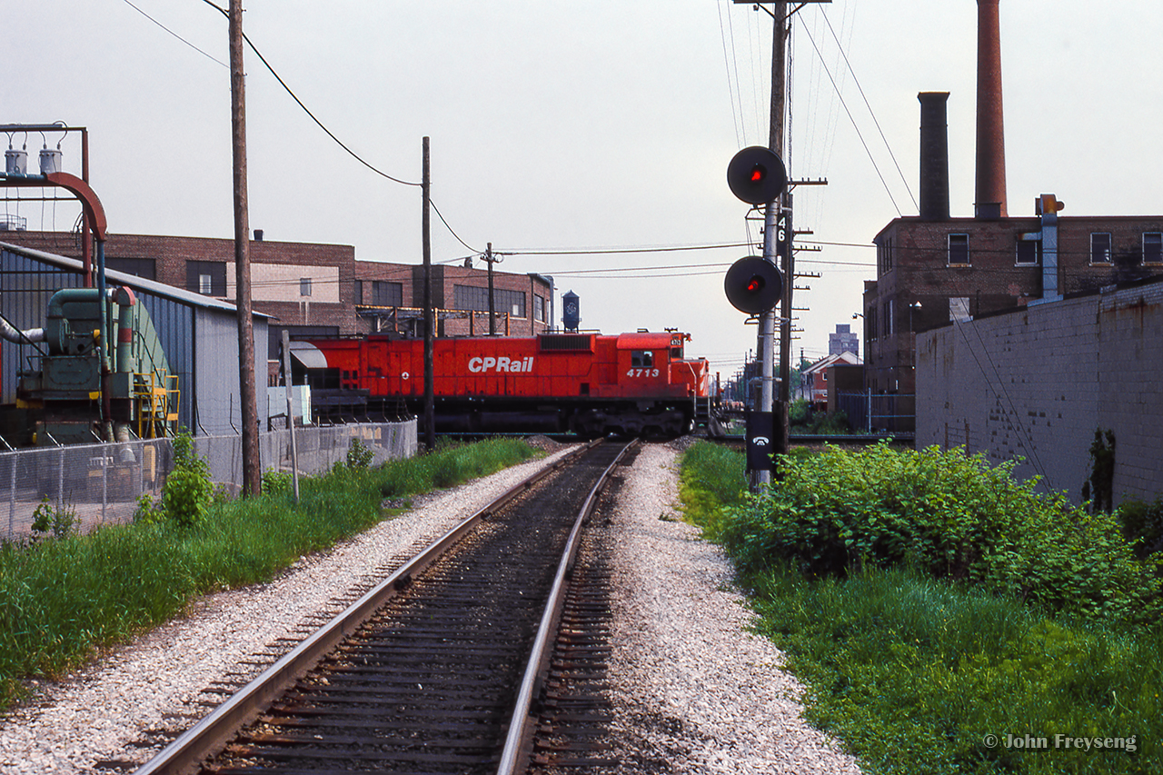 Looking south along the CN Newmarket Sub at Davenport diamond, a westbound train behind three big MLWs cuts through the scene.  This scene has changed dramatically in recent years with the elimination of the diamond in favour of an overpass (Eric Fallas shot here) for the Metrolinx-owned portion of the Newmarket, carrying GO Transit and VIA Rail trains over CPKC's North Toronto Sub.

Scan and editing by Jacob Patterson.