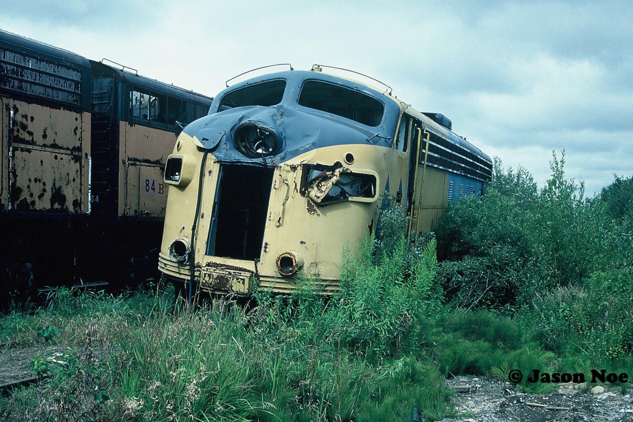 On September 9, 1991, while travelling southbound at 45mph, Ontario Northland Railway (ONR) train 122 “The Northlander” was unintentionally diverted off the mainline through an open switch at Mile 225.8 of the Newmarket Subdivision in North Bay. The train had just been turned over to CN control for its journey to Toronto. Now lined on a siding, the train collided with CN SW1200RSu 7304 that was on a yard assignment. The switcher was sitting 257 feet from the main track, situated on a wye, waiting for the passenger train to clear. The resulting collision caused injuries to 60 passengers and 11 railway employees with 67 being minor and 4 serious. Many of the passengers were injured when falling luggage from overhead baggage compartments became projectiles. ONR FP7A 1517, which was leading 122, was heavily damaged and its cab was entirely separated from its body, which had overturned. Trailing unit FP7Am 1985, was being used as an electric generator had also derailed and suffered damage as well. Both ONR units were retired following the collision while CN 7304 would go on to be repaired after suffering significant damage to its cab. Ironically, it is still operating today at the Steel Centre in Parkdale Yard in Hamilton.

Almost three years after the collision, FP7Am 1985 is pictured languishing in the tall weeds seemingly forgotten at ONR’s deadline situated in the North Bay Yard with its wreck damage evident. According to the Trackside Guide the unit was retired in 1993 and was eventually scrapped in 2000.