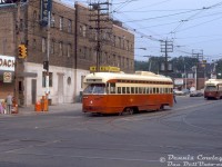 TTC PCC 4744 in "subway red" paint (A13-class, built by Pullman in 1947 for Birmingham, Alabama) turns westbound onto The Queensway off Roncesvalles on a Dundas short-turn, returning to nearby Roncesvalles Carhouse after morning rush hour. TTC 4653 (A11-class, built by Pullman in 1946 for Cleveland) follows behind, another Dundas car returning to the carhouse. Both are passing the old Edgewater Hotel and the Gray Coach terminal in Sunnyside.<br><br><i>Dennis Cowley photo, Dan Dell'Unto collection slide.</i>