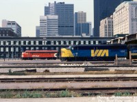 VIA FPA4 6762 and F9B 6622 sit on a passenger consist on Track 10, poking out of the west end of Union Station's train shed in downtown Toronto. A few tracks down, VIA's "The Canadian" consist sits with on Track 4, with CP FP7 1424 (and GP9 8517) on the head-end. VIA had taken over CP's passenger services last fall, and plenty of the ex-CP power was still in full CP colours (the 1400-series F-units were sold to VIA, but the steam generator-equipped GP9's were retained by CP and used as passenger protection power when needed).<br><br>The brown 3-story brick building in the background is the old CN Express Building (cut down and turned into park of the Skywalk in the 1980's). While Union Station itself isn't visible (other than the train shed), part of CP's Royal York Hotel is on the right.<br><br><i>Barry Schroeder photo, Dan Dell'Unto collection slide.</i>