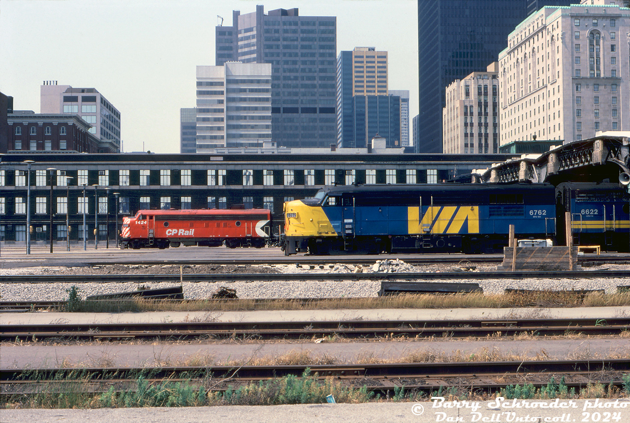 VIA FPA4 6762 and F9B 6622 sit on a passenger consist on Track 10, poking out of the west end of Union Station's train shed in downtown Toronto. A few tracks down, VIA's "The Canadian" consist sits with on Track 4, with CP FP7 1424 (and GP9 8517) on the head-end. VIA had taken over CP's passenger services last fall, and plenty of the ex-CP power was still in full CP colours (the 1400-series F-units were sold to VIA, but the steam generator-equipped GP9's were retained by CP and used as passenger protection power when needed).

The brown 3-story brick building in the background is the old CN Express Building (cut down and turned into park of the Skywalk in the 1980's). While Union Station itself isn't visible (other than the train shed), part of CP's Royal York Hotel is on the right.

Barry Schroeder photo, Dan Dell'Unto collection slide.