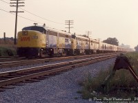 A morning westbound VIA passenger train speeds through Scarborough with three MLW's on the head-end: FPA4 6788 and 6769, sporting VIA paint and logos, and an unknown 6800-series FPB4 still in CN zebra stripe paint. Nine passenger cars trail, including two baggage cars (most appear to still be in CN paint, as the new "VIA" branding was barely two years old at this point). It won't be long before the train covers its final miles and arrives at Union Station in downtown Toronto.<br><br>The location is just before Greenwood Avenue on CN's Kingston Sub. As per track diagrams, the train is heading westbound on the "west mainline", with the next track over the "east mainline", then the Y-200 service track, and the track bumper at the end of the old Greenwood Avenue team track (Y-012, appears to be out of use at this point). North of the mainline track was another service track, Y-230, that lead into the back of the <a href=http://www.railpictures.ca/?attachment_id=30975><b>TTC's Greenwood Yard</b></a> nearby.<br><br><i>Original photographer unknown, Dan Dell'Unto collection slide.</i>