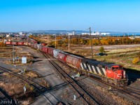 Viewed from the Central Ave overpass, a CN afternoon extra utilizing CN SD60F 5504 shoves a string of grain empties through TC04 and over onto TC92 to be inspected for the evening run of train A437. In the background a pair  SD60F's sit on the Northern Wood lead- named for the large lumber mill that use occupy the lands to the right out of frame. As of 2024, the former Northern Wood and neighbouring property (the old CN ore dock) have been  reorganized into the Midcontinent Terminal. Currently a scrap company ships loaded gons out of the site. More info on the terminal can be found <a href="https://midcontinentterminal.com/about-us"> here.</a>