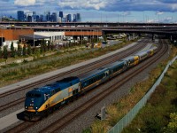 VIA 67 passes the skyline of downtown Montreal as both head end crewmembers wave.