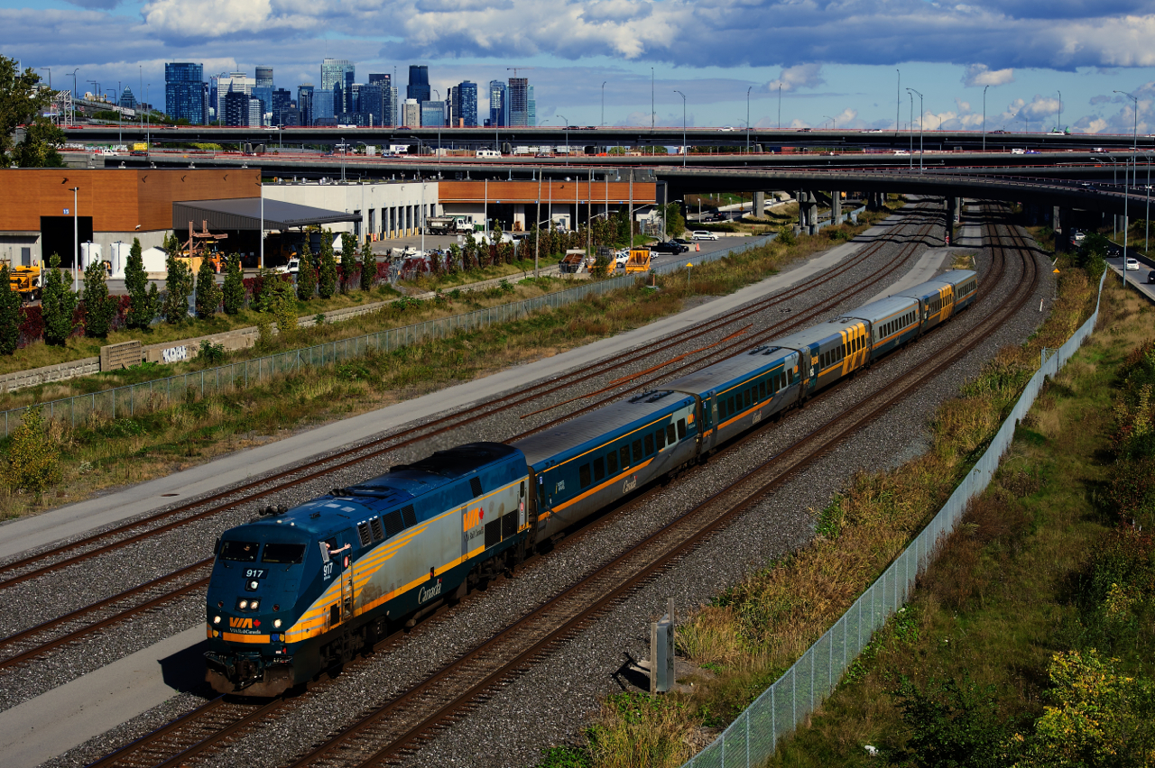 VIA 67 passes the skyline of downtown Montreal as both head end crewmembers wave.