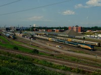 A variety of VIA Rail equipment is seen at the Montreal Maintenance Centre from a passing REM train.