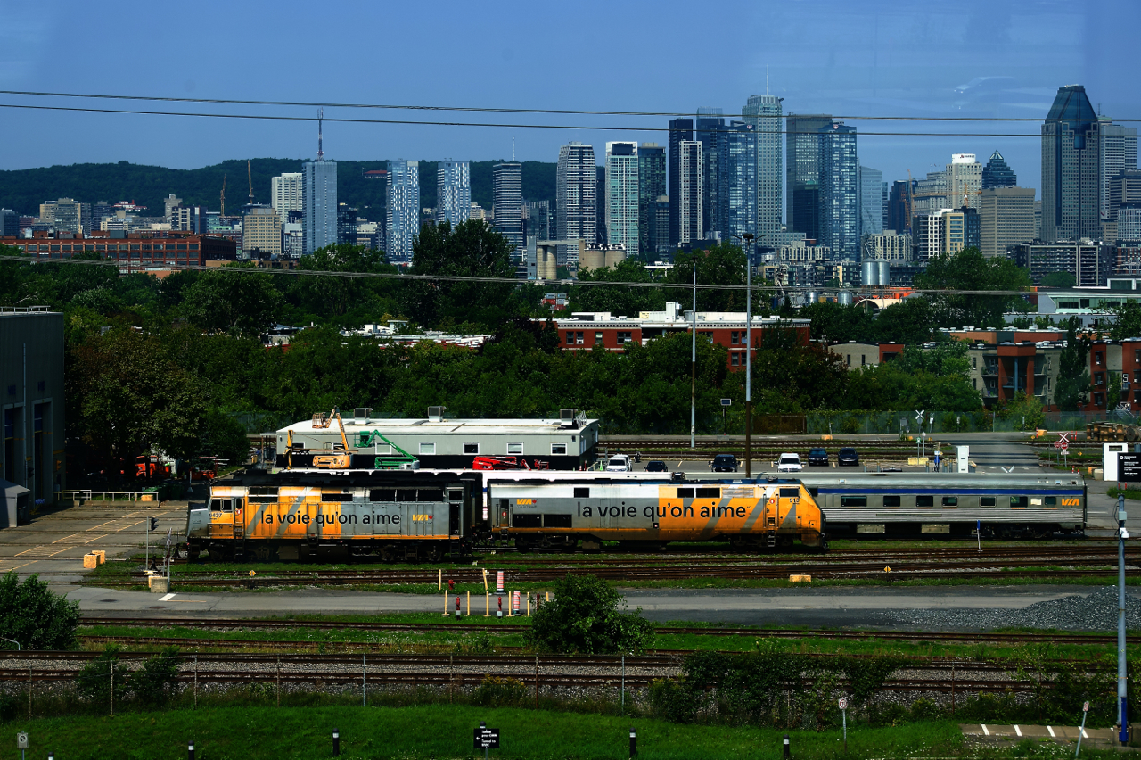 A wrapped F40 and P42DC are seen at the Montreal Maintenance Centre from a passing REM train.