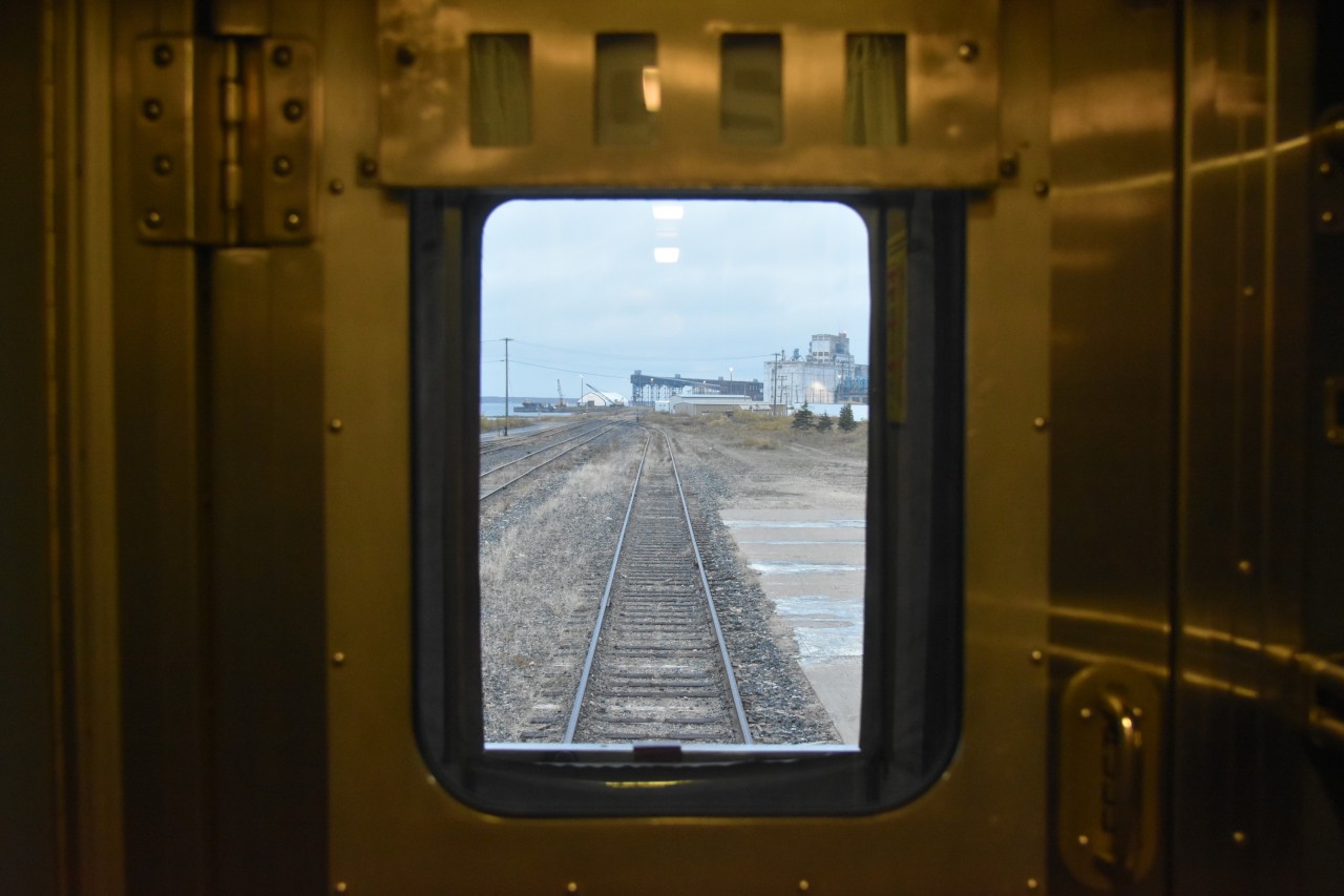 Doo, Doo, Doo, Lookin' out my back door ????  
Prior to VIA 692 The Hudson Bay departing Churchill, MB the evening of September 19, 2024 I snapped this pic through the rear door window and vestibule of VIA 8224 Chateau Roberval sleeping car. 
The Churchill grain silos and elevator still stand vacant, waiting a decision on their future use at this deep water port. 
The station track has been nicely rehabbed with new ties, new rail, and a lift, level, line and tamp.