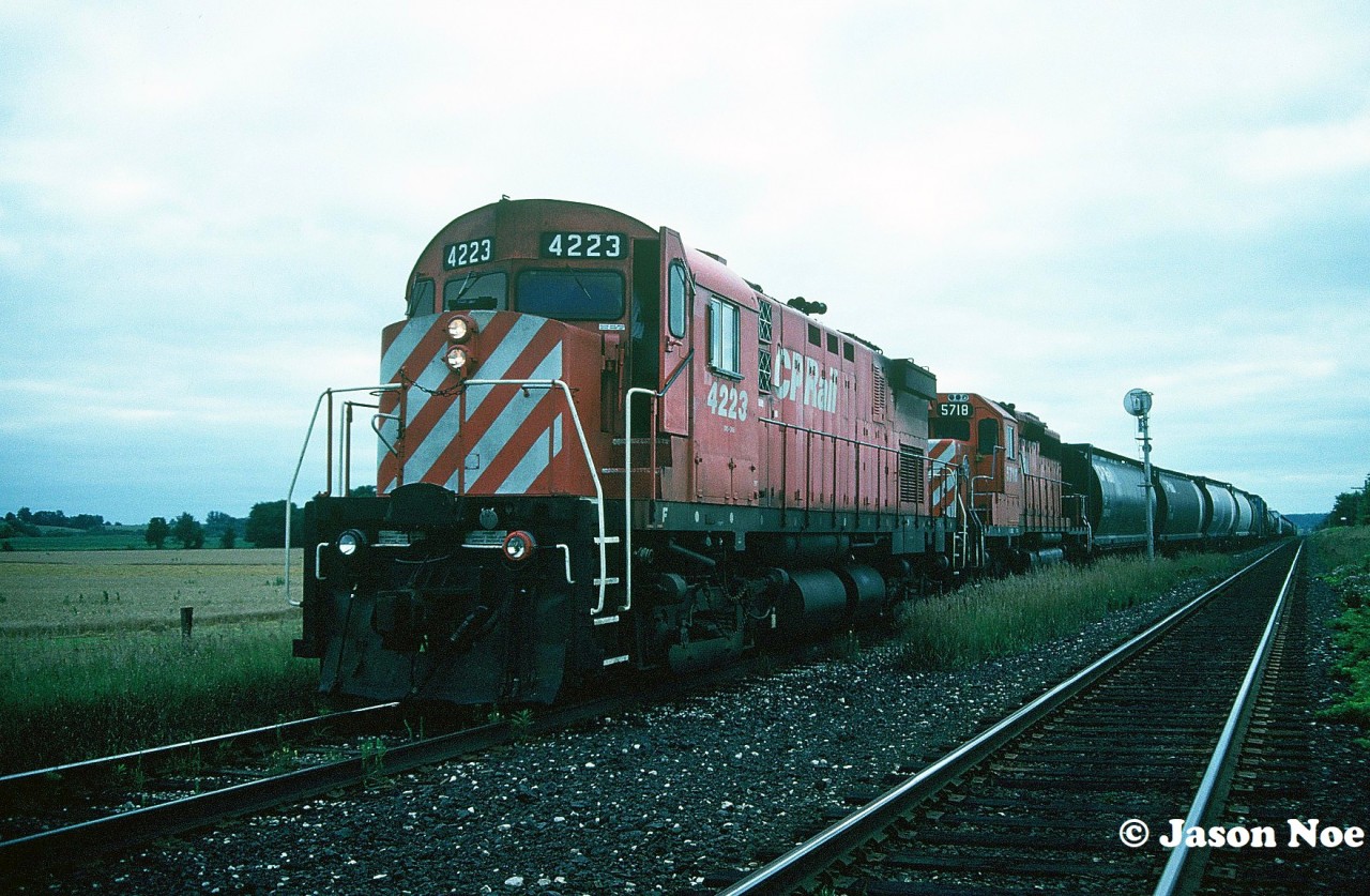 A short CP eastbound with C-424 4223 and SD40-2 5718 are pictured waiting at the east siding switch Wolverton for a meet with a westbound on the Galt Subdivision. The siding is situated just west of the town of Ayr, Ontario and is now home to a large CPKC yard and auto compound.