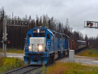  Unfortunately, I suppose, it was a bit of a downer to be up in these northern parts of Manitoba on a day that was drizzly and dull.  But on the "bright" side, this shot otherwise would have been almost directly into the sun.
Twice weekly Keewatin Railway's mixed train runs from The Pas to Pukatawagan, an isolated town that relies on the railroad for its very existence. The Mixed brings supplies, building materials, vehicles as well as an opportunity for some of the town folk to ride it back south to The Pas for shopping trips.
 In this view, PRLX 2269 and 2265 power the Mixed across Manitoba highway #10 (route to Flin Flon) as it heads northward after a stop at Cranberry Portage to pick up three gons and a few passengers.