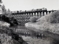 Heading for Edmonton’s ex NAR Dunvegan Yards on its second day of travel from Waterways, a Mixed Extra South with CN 1078 + 1080 (ex NAR 303) + 1072 (ex NAR 311, nee CN 1072) is crossing the timber trestle over the Sturgeon River at mileage 9.7 on Wednesday 1981-09-30 at 1232 MDT.

<p>Until the end of 1980, this was Northern Alberta Railways’ Edmonton sub., logically renamed to the CN Westlock sub. when they took over.  Somewhat to my surprise, aside from renumbering NAR locomotives to the CN plan, the NAR diamond symbol and name and unit names (Bishop Grouard and Twelve Foot Davis) were left intact in the first CN year.