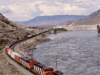 Running alongside the Thompson River between Ashcroft and Savona and enroute next crew change at Kamloops on Thursday 1987-05-21, an eastward intermodal freight powered by CN 5281 + 5291 + 5439 is at mileage 31.8 and just about at the east end of the siding at Walhachin.