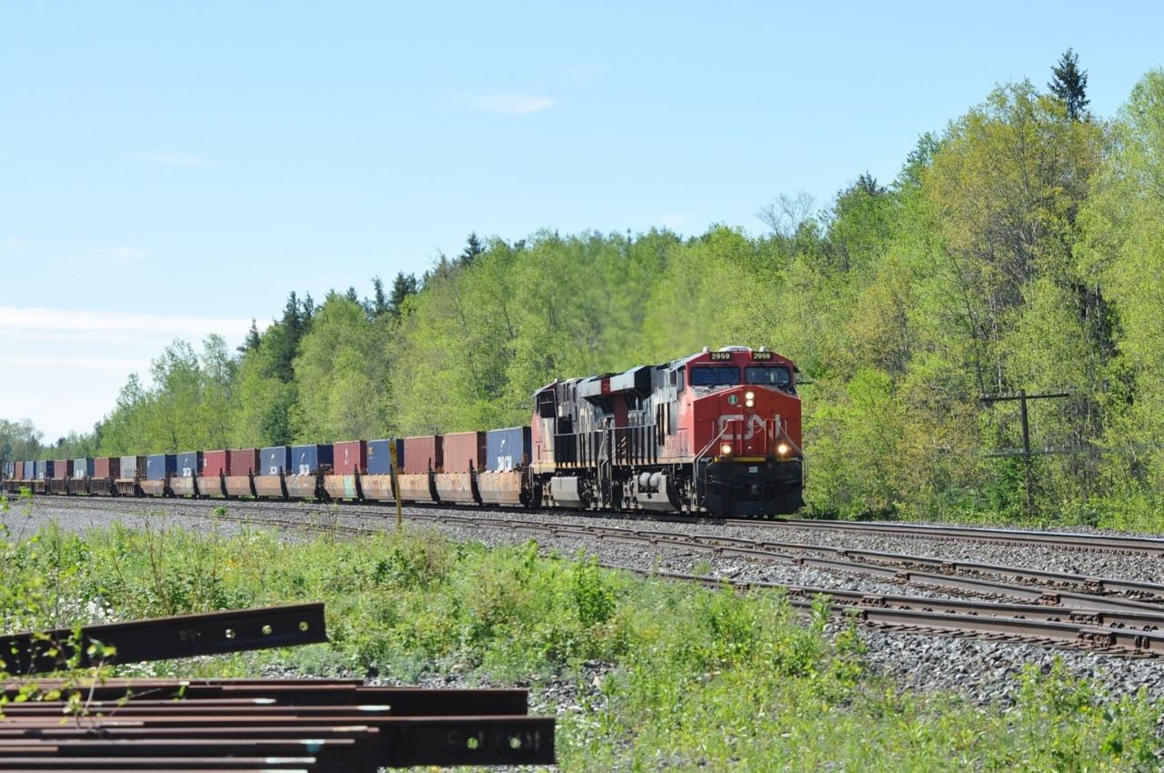 Another one of CN's many double-stack intermodal trains heads west through Milnet, Ontario on July 2, 2018 with a large cut of single stacks on the head end.  Power for the train is the 2959 and 2952.