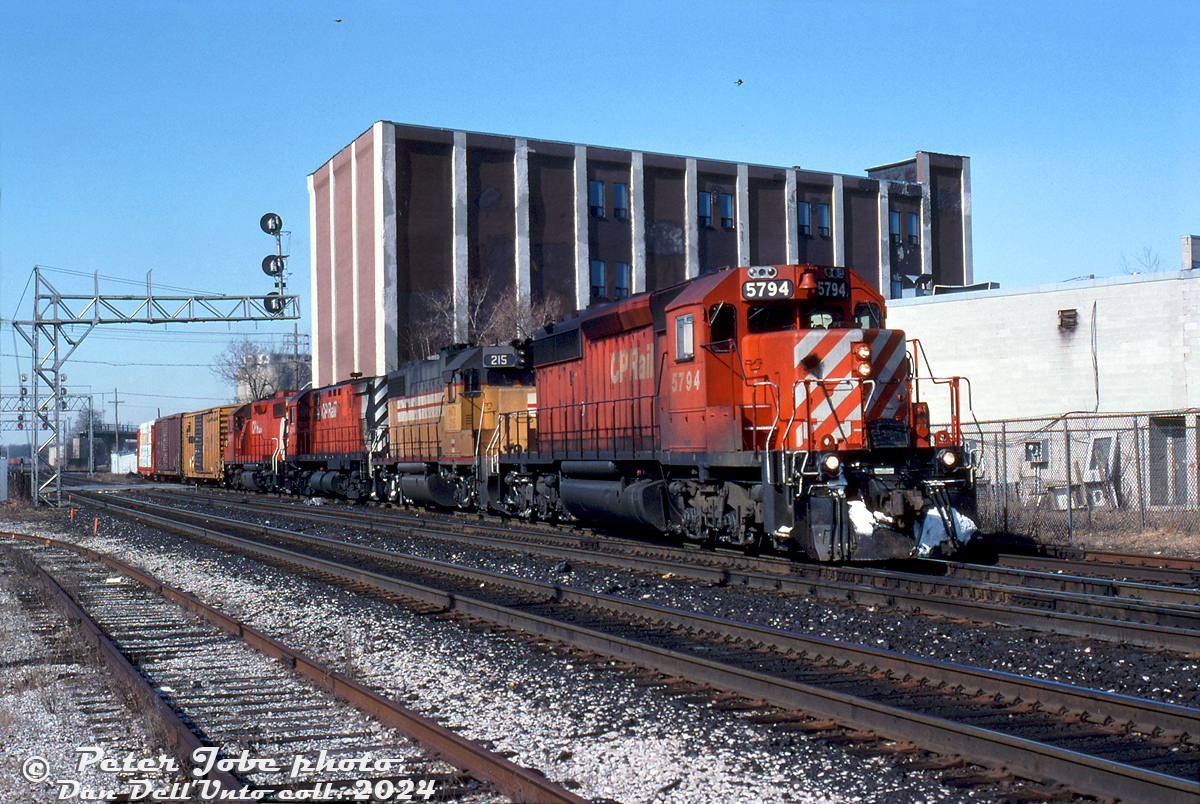 CP SD40-2 5794, leased HATX 215 (a leased ex-UP/MP GP38-2), C424 4241 and GP38-2 3075 lead train #934 off the MacTier Sub onto the North Toronto Sub at Osler Street, heading eastbound for CP's Toronto (Agincourt) Yard just before noon.

The two main tracks of CP's North Toronto Sub are in the foreground, with the track at the bottom left being the old S-Yard lead that curved south and ran along the east side of the rail corridor to serve a small handful of customers between West Toronto to Dundas Street (the "Old Bruce" TG&B service track, now the West Toronto Railpath).

The signal bridges in the distance bracket the CN-CP West Toronto diamond, near the northern approach of the ill-fated Old Weston Road railway bridge that can be seen in the background (the main span over the tracks having been already removed). And a derailment in the late 2000's took out that large warehouse off Osler Street just behind the power.

Peter Jobe photo, Dan Dell'Unto collection slide.