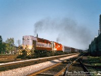 Canadian Pacific RS10 units 8576 and 8476 motor through Toronto's Parkdale neighbourhood on the Galt Sub, handling northbound train #11 "The Canadian" just out of <a href=http://www.railpictures.ca/?attachment_id=55182><b>Union Station</b></a> downtown. The train has just passed Brock Avenue underpass and is closing in on <a href=http://www.railpictures.ca/?attachment_id=14408><b>West Toronto Station</b></a>, where it'll make its final stop in the city before taking the <a href=http://www.railpictures.ca/?attachment_id=46245><b>connecting track</b></a> across the West Toronto diamonds to the MacTier Sub on their trip north to <a href=http://www.railpictures.ca/?attachment_id=53634><b>Sudbury</b></a>. On the left are houses off Delaney Crescent, on the right some newer apartment buildings off West Lodge Avenue. The switch in the foreground is for a service track that came off here and ran north along the west side of the corridor to West Toronto, serving a few industries.<br><br>Today's passenger train consists of one of CP's 2200-series lightweight steel "curve-side" coaches up front (likely deadheading), two similar curve-side baggage cars (one still painted fully maroon), a Budd stainless steel baggage-dorm, and possibly another 2200-series coach in maroon (hard to tell, could just be in shadow) in-service, followed by the rest of the train of stainless steel Budds. The old lightweight steel cars dated from 1947-1950, built by NSC and CC&F, and were initially painted in full maroon with gold lettering. In the mid-1960's, CP repainted some coach and baggage variants in silver paint to match the stainless steel fleet, and gave them a maroon (some later red) letterband. Since they were used as-needed on The Canadian (and CP was getting a little tardy with its older passenger fleet), paint wasn't much of a priority, and old maroon and silver/maroon cars showed up well into the action red CP Rail era. A bunch were even transferred to VIA, but saw little if any use.<br><br>CP's fleet of freight/passenger RS10's equipped with steam generators were common on the Sudbury-Toronto runs, mixed in with <a href=http://www.railpictures.ca/?attachment_id=42540><b>4000-series FP7</b></a> and FPA2 units. When CP was phasing out it's 244-powered Alco/MLW fleet in the mid-70's to early 80's, some RS10's hung on as passenger protection power for VIA's Canadian. The final two were used in <a href=http://www.railpictures.ca/?attachment_id=29820><b>commuter service out of Montreal</b></a> in 1983.<br><br><i>Original photographer unknown, Dan Dell'Unto collection slide (duplicate).</i>