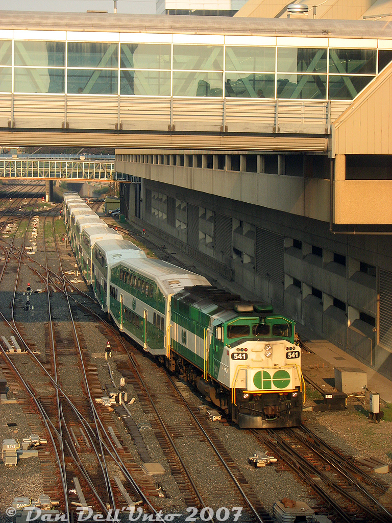 Early worm gets the bird: it's 7:15am, and GO Transit F59PH 541 glints in the morning sun as it pushes its consist out of Union Station. Having come in on Lakeshore East train #425 westbound from Oshawa (6:12-7:12am), it's now operating as equipment move 456 deadheading west empty, to begin train #456's eastbound run on the Lakeshore Line from Oakville station back to Union (7:58-8:21am).

The train has just departed the Union Station train shed, and is ducking under the Metro Convention Centre's pedestrian bridge on the approach to John St. interlocking tower. On the right is the "fence track", used for parking business cars, special passenger equipment and maintenance equipment. Back in the day, railroad executives often parked their private business cars here if they were going into town or staying at the Royal York Hotel nearby.