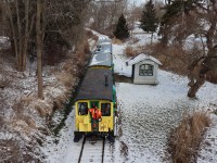 PSTR Santa Treats Train (1st ride of 3 this day) is returning to Port Stanley from Whyte’s Park.  The train consisting of three cars 66, 62 and 63 plus the Little Red Caboose 602, filled with excited children and parents, is alongside Union Depot (previously the North Pole). Port Stanley Terminal Rail’s L1 Stanley (although perhaps not visible) is pushing its Christmas train downgrade through the Kettle Creek Valley on the historic tracks of Port Stanley and London Railway. Santa Claus hopped on and off the train, this year, when passing through the storage yard located a short distance from the PSTR station.  The timely skim of snow overnight adds to the scene and festive occasion. 
This photo may qualify for the Time Machine in conjunction with a photo by Greg Roach ID: 21596 taken at Union (49 years previous) on a UCRS Excursion from Toronto to Port Stanley.
