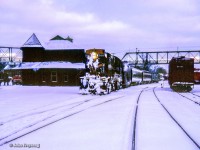 CN train 672 from Owen Sound arrives at Palmerston with conventional passenger equipment trailing RS18 3105.  While typically equipped with RDCs, conventional equipment would return to the branchlines during the Christmas season, while the Budd cars were added to Niagara-bound trains.

<br><br>Several UCRS members made the trip to Palmerston on Boxing Day, 1962, to ride the wayfreight to Kincardine. The train, which ran as an extra, was not using a van for the tailend crew due to a shortage, but rather an old combine, giving the train the appearance of a mixed train. Regular passenger service on the Kincardine Sub still remained in 1962 in the form of one RDC trip. With releases signed, UCRS members were permitted to ride the "mixed," and with two at a time permitted to ride the flanger which departed for Listowel behind a pair of MLW RSC-13s; 1709 and 1732.

<br><br>Further details can be found in the February 1963 UCRS newsletter.

<br><br>Later that day, <a href=https://www.railpictures.ca/?attachment_id=54310>Extra CNR 1732 at Brussels.</a>

<br><br><i>Scan and editing by Jacob Patterson.</i>