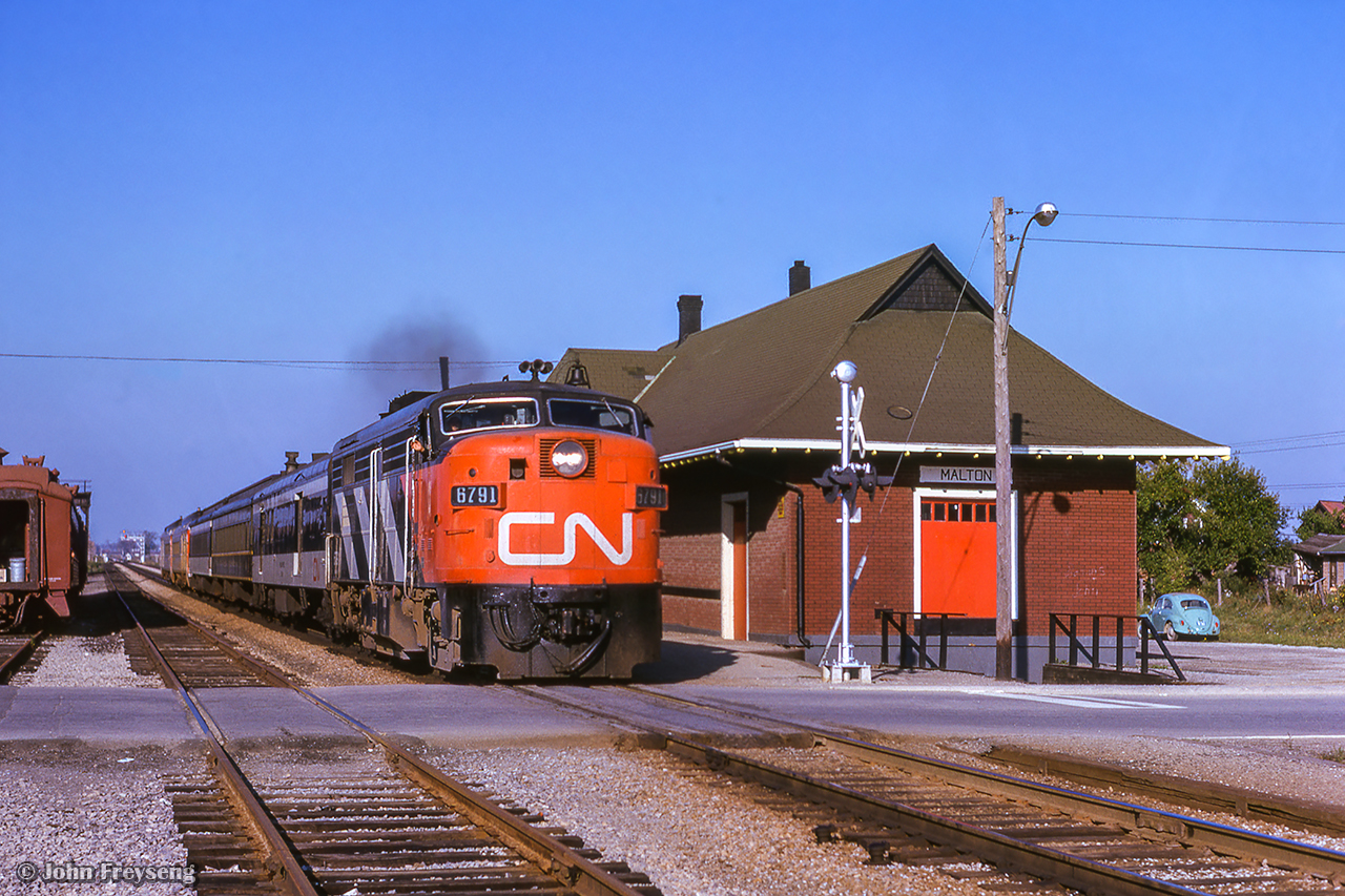 The engineer aboard train 628 from Stratford to Toronto gives a wave as the train flies past Malton station, crossing Scarboro Street, today the only grade crossing remaining on the Weston Sub.  With GO Transit assuming commuter operations in 1974, a new station was built further east, with this 1912 structure being demolished around the same time.

Scan and editing by Jacob Patterson.