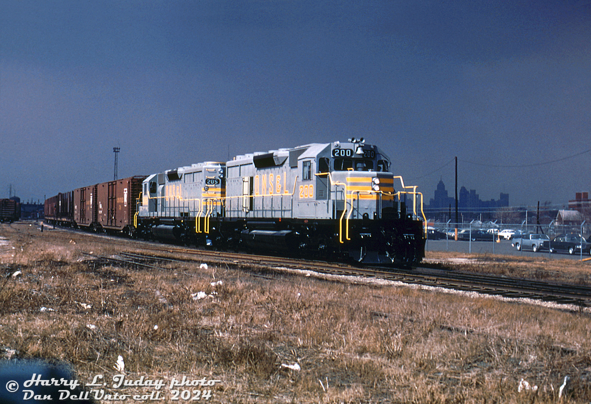 Freshly minted from the GMD London assembly plant, brand new Quebec, North Shore and Labrador SD40 units 200 and 205 are out on a test run on Canadian Pacific, seen at what appears to be the east end of CP's Windsor Yard at Tecumseh Street. The "storm lighting" in this photo is rather captivating, with part of the Detroit skyline looming in the shadows in the distance.

Both units were part of a six-unit SD40 order (QNS&L 200-205) built in February-March of 1969 by GMD. Iron ore hauler QNS&L at that time had a roster of mainly GMD GP7 and GP9 locomotives built in the 1950's, so this order was their first 6-axle high horsepower second-generation diesel purchase. They would place another order in 1971 (206-220), and SD40-2 orders in 1972, 1973 and 1975, retiring a lot of their early Geep fleet (a good number were sold to Bellequip and later Precision National for lease service in the early 70's).

200 would later be retired and rebuilt as KCS 696, while 205 would become CP 5401.

Harry L. Juday photo, Dan Dell'Unto collection slide