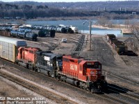 An NS train with CP power running over a CN line: NS #328 (the autoparts train that ran from St. Thomas to Buffalo) rolls through CN's Stuart St. Yard in Hamilton on the Oakville Sub, having come off the Dundas Sub via "the cowpath" at Hamilton Junction. Power today is St. Lawrence & Hudson (CP's eastern subsidiary/operating unit at the time) SD40 5532, NS B23-7 4013 (check out the stubby high nose), and CP SD40 5536. Burlington Bay and the York Blvd high level bridge add some scenery to this drab March scene.
<br><br>
<i>Bill McArthur photo, Dan Dell'Unto collection slide.</i>