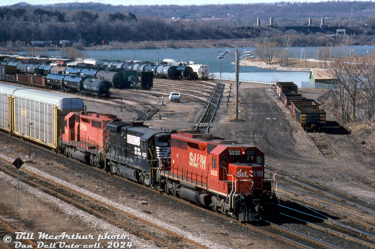 An NS train with CP power running over a CN line: NS #328 (the autoparts train that ran from St. Thomas to Buffalo) rolls through CN's Stuart St. Yard in Hamilton on the Oakville Sub, having come off the Dundas Sub via "the cowpath" at Hamilton Junction. Power today is St. Lawrence & Hudson (CP's eastern subsidiary/operating unit at the time) SD40 5532, NS B23-7 4013 (check out the stubby high nose), and CP SD40 5536. Burlington Bay and the York Blvd high level bridge add some scenery to this drab March scene.

Bill McArthur photo, Dan Dell'Unto collection slide.