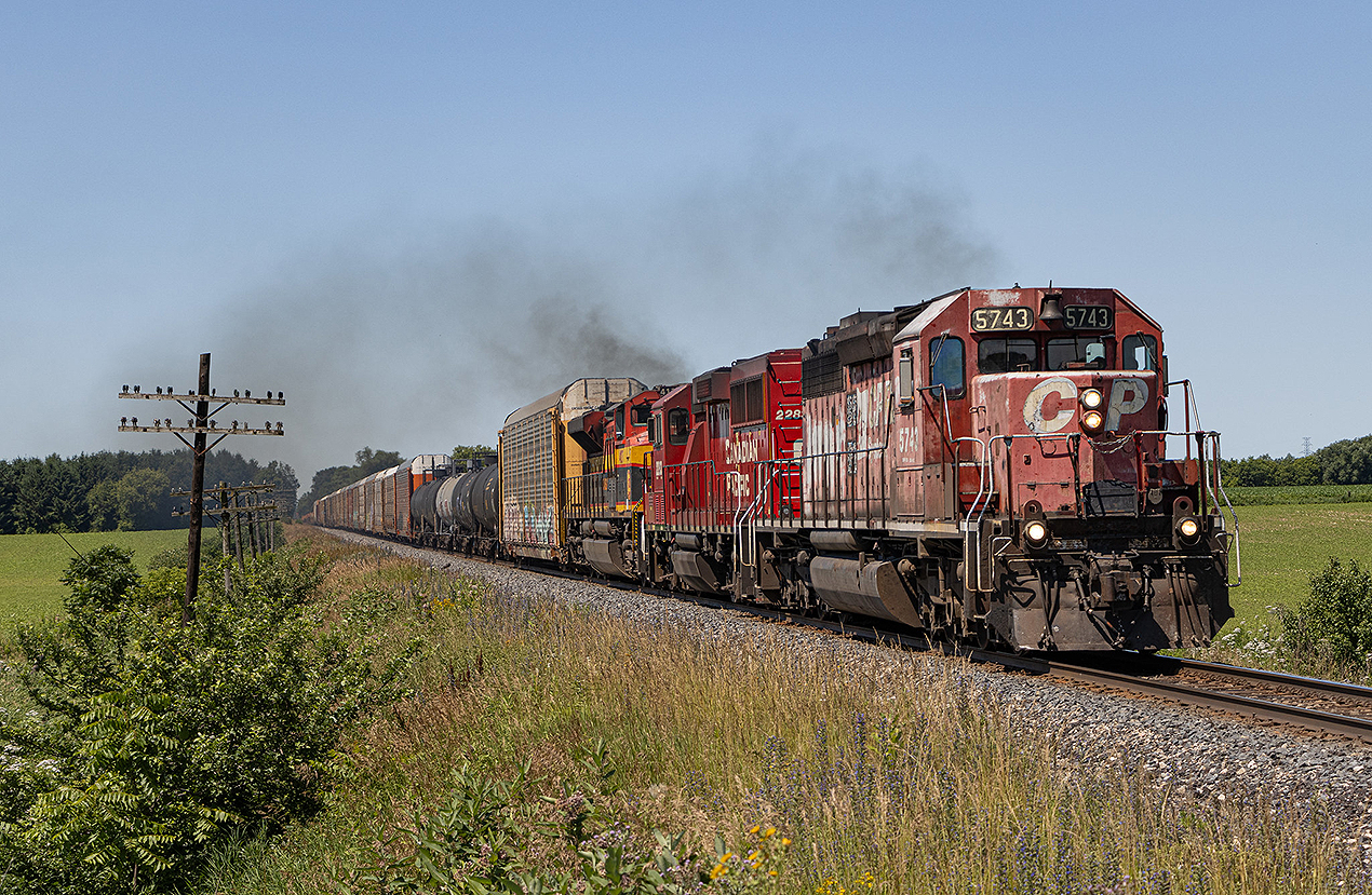 The "CP Rail System" returned for Canada Day of 2024!  

CPKC 2-H92 (although it was reported with various other symbols) hauls through Thamesford just after 11 AM with the "rescue" unit for 135 a few days prior - 'Dual Flag' SD40-2 #5743.  I and many others thought for sure that this unit would have been wyed in Windsor or Detroit for the return trip east - but somehow, it emerged out of Walkerville Junction just after 6 AM in the lead position of (at the time) 134.  This was a good day to not sleep in.  This was one of two mainline SD40-2 leaders in the year for London and the surrounding area.  It was great getting to see everyone out and about for this one.

July 1, 2024.