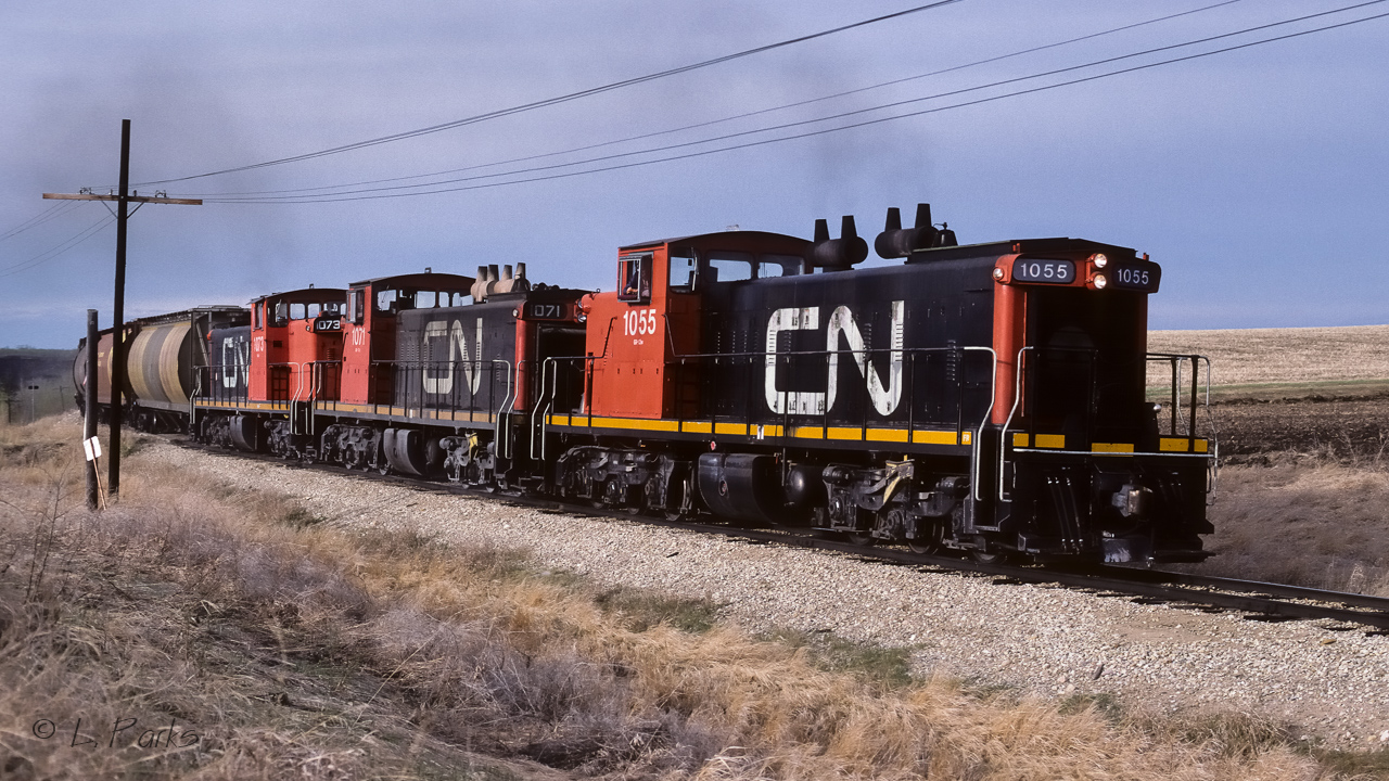 An extra going back to Edmonton with a few loads of grain and some empty tanks. Photo taken at mile 12.7 just south of Gibbons. The train was ascending the last of the hill up from the Sturgeon river. The valley can be seen to the left of the hoppers. In less than a 1/2 mile, the track straightens out and goes directly south to the junction switch.