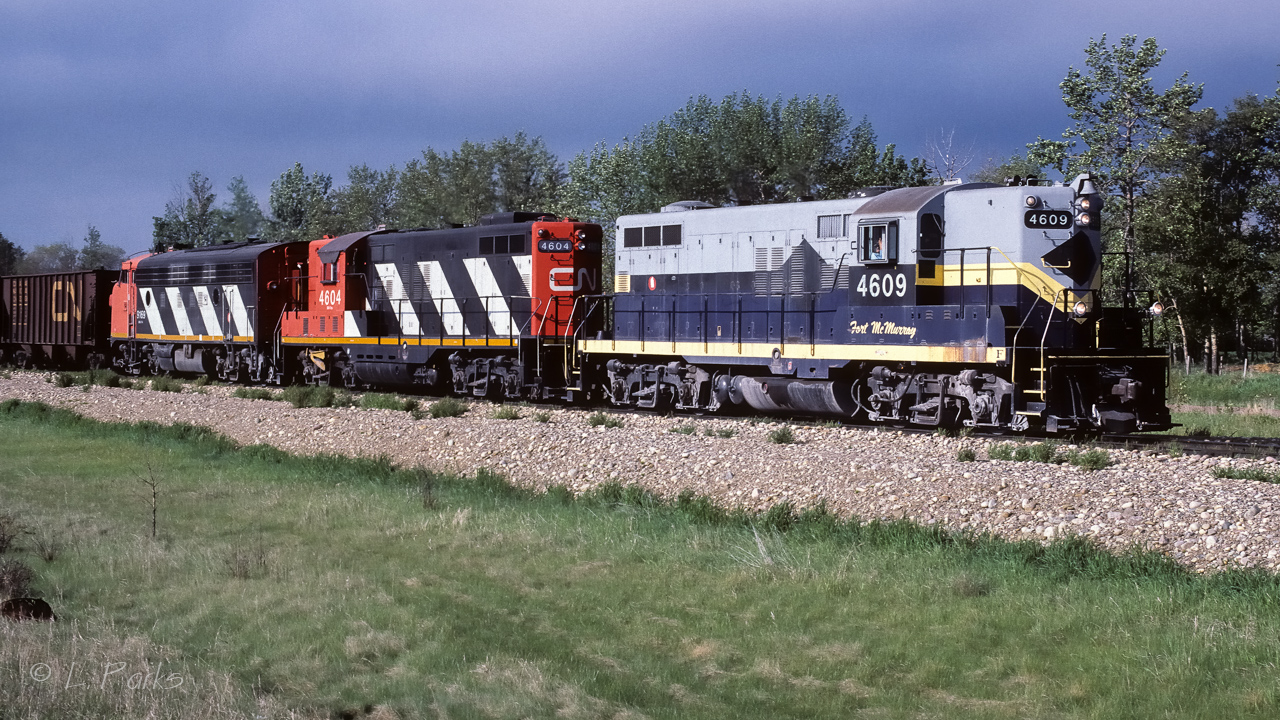 First thing in the morning finds a unit train of empties on the way north to exchange them for loaded hoppers. As far north as this train would go, the there and back time was not that long typically. Like this day, most unit trains would head out between 7:00 and 8:00 and return the next day anywhere from 16:00 to 20:00. Photo taken just north of Egremont with storm clouds already making an appearance in the west.