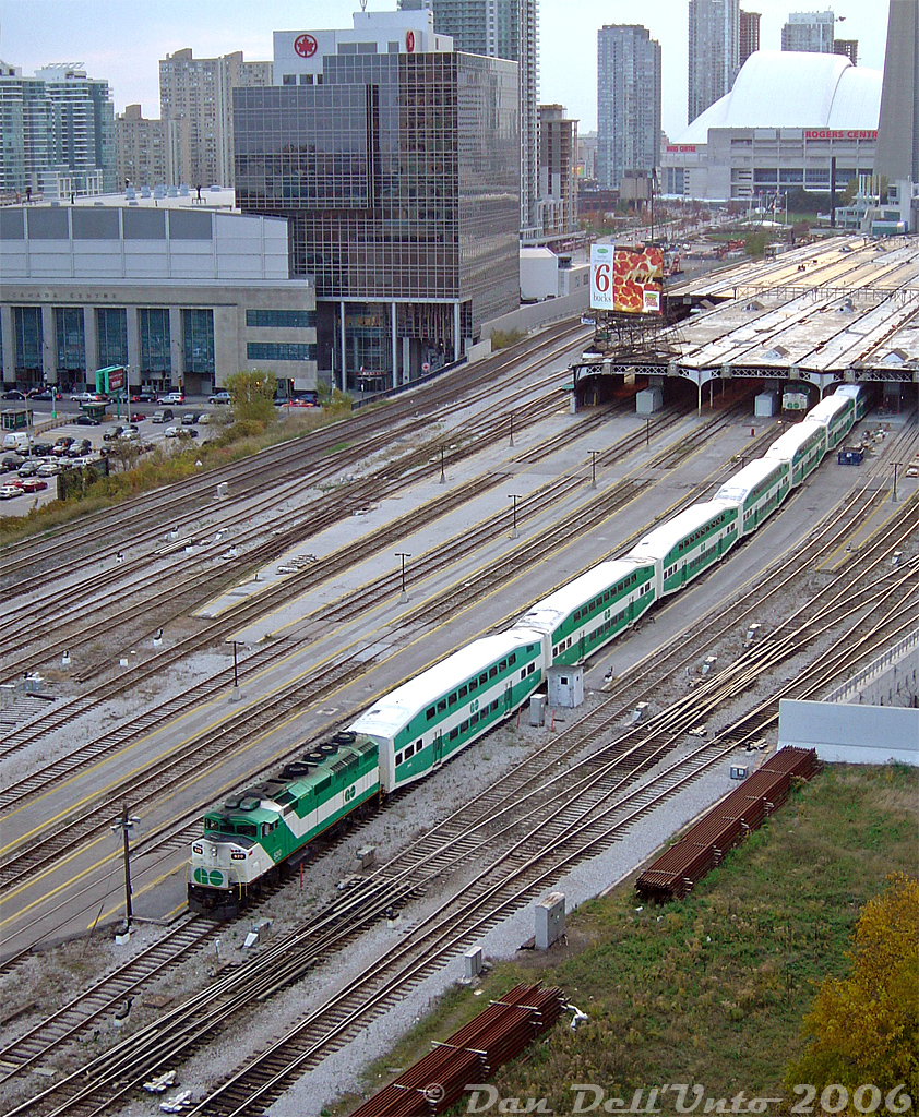 GO Transit F59PH 520 slowly pushes its train westward into Track 6 of the train shed at Toronto's Union Station downtown, with another F59PH poking its nose from underneath on Track 7 as PM rush hour is in full swing.

Quite a few things have changed since this 2006 view of the USRC and surrounding area near Scott Street interlocking tower, including a new condo being built on the small parcel of land and nearby parking lot at the bottom right (blocking this condo's view). The Air Canada Centre (note logos and lettering) is now Scotiabank Arena, and a lot more condos and office towers populate the downtown skyline. That parking lot on the left is now home to an office tower with GO's new bus terminal in it. The shuttered ex-CPR John St. Roundhouse in the background is now home to a railway museum, among other things. And GO 520, retired in 2009, went on to work a short stint leased to VIA, then SoCal on Metrolink, and finally ended up at a start-up passenger operation in Mexico!