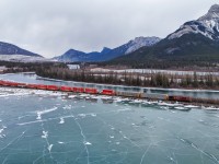 Winter in the Rockies.  CPKC 105 highballs towards Gap, as someone skates on Gap Lake, just west of Exshaw. 