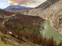 The Lytton area was devastated by a wildfire in the summer of 2020, and the canyon still wears the scars of the fire, with scorched trees and brush along the right of way.  Two years after this fire we catch CN Q 10451 02 rolling down the CP Thompson Sub, as another fire rages in the mountains above Lytton, creating overcast conditions on an otherwise sunny day in the canyon. 