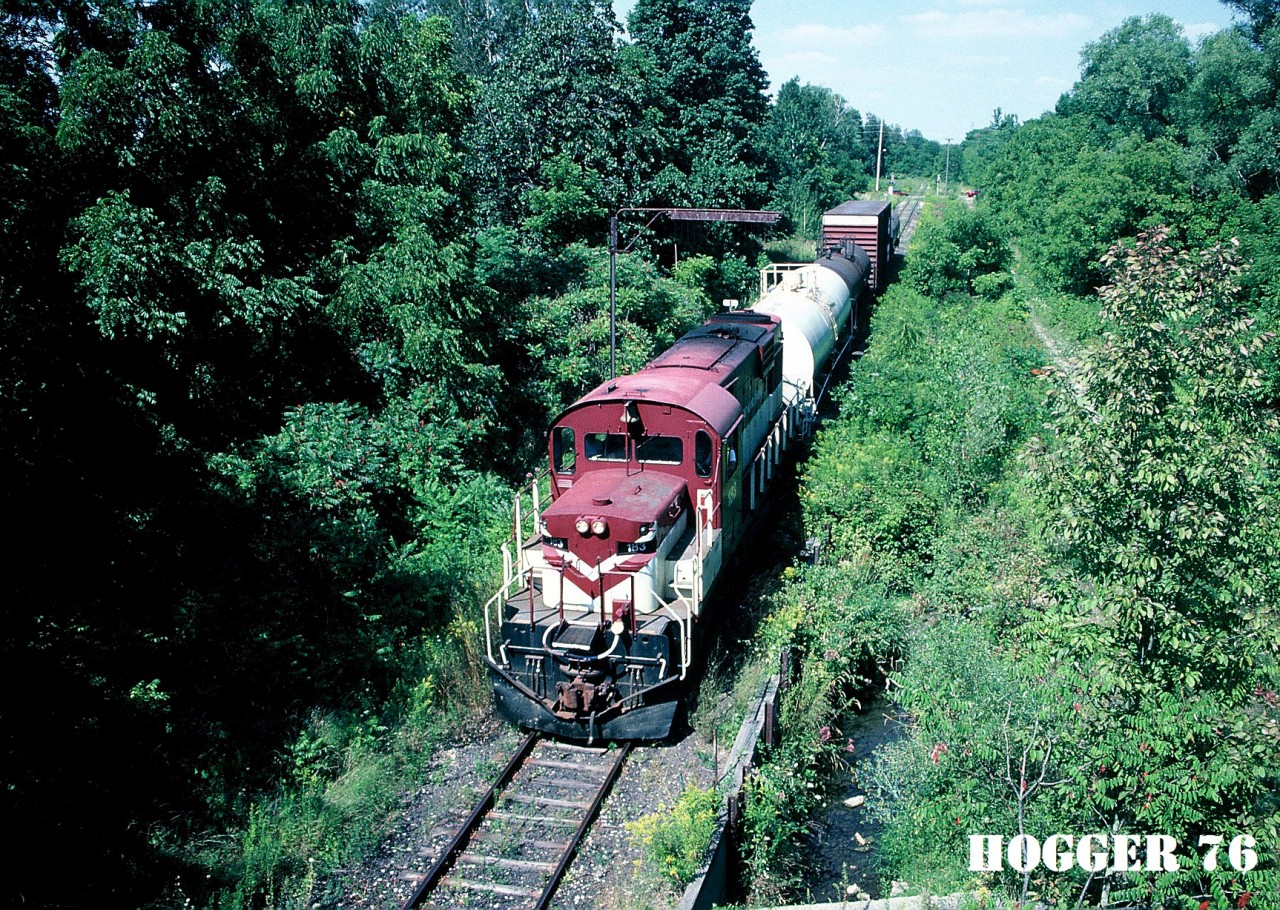 Ontario Southland Railway RS18 183 south arrives in Tillsonburg, Ontario with a small train from the CP interchange at Ingersoll. The train is going under the classic “telltail” on the Tillsonburg Spur (former CP Port Burwell Subdivision). Built with a low nose in 1968, RS18 183 is ex-INCO 208-3. The view was from the now abandoned Caso Subdivision, which crossed over both the CP Port Burwell Subdivision and CN Burford Subdivision at this location.