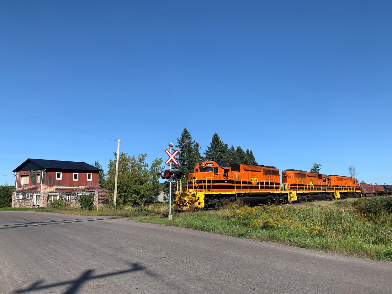 Featuring a level of horsepower rarely seen on the Huron Central, SUSM (Sudbury - Sault Ste. Marie) features a lash up of 9000 total horsepower from its sister roads. With a train made up of empty coil cars, bulkhead flats, a few gasoline tankers and boxcars, the train coasts across the Gordon Lake Rd. crossing due to a slow order. This train will soon finish the last leg of its trip, before quickly flipping around with a fresh crew, hauling loaded coils, plate steel and calcium carbonate cars east to Sudbury, needing all 9000 horses the lineup can provide.