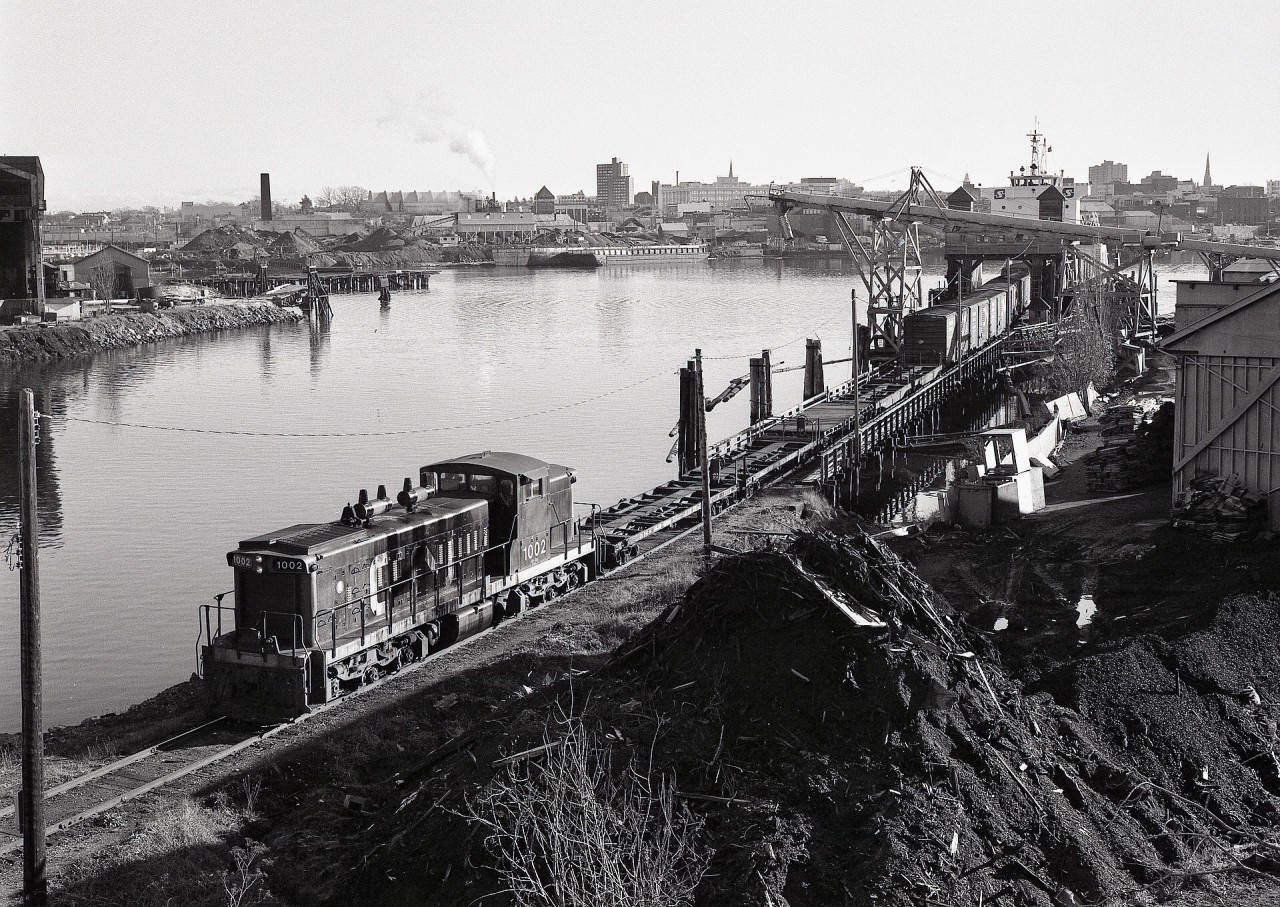 Canadian National’s Cowichan subdivision on Vancouver Island was separated by bridge conditions, so traffic from the mainland arrived Victoria via barges to a slip at Point Ellice just below the Bay Street road bridge.  On Tuesday 1978-12-05, yard engine CN 1002 was switching self-propelled rail barge SEASPAN GREG, with evidence of cold-weather extensive idling drooling down the sides of the engine hood.

On the other side of the harbour, directly above 1002, is another rail barge slip, that one for serving the Victoria Machinery Depot’s facility.