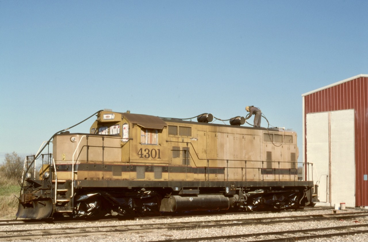 Carrying on from CWRL 7438 as posted last Sunday, here is CWRL 4301 on the opposite end of the engine shed at Warden on Saturday 1991-10-05, with grit blasting underway at 1040 MDT in preparation for a new paint job.

CWRL 4301 was nee Pittsburgh & Lake Erie 5680, an EMD GP7 serial 14577 of 1951-09, as rebuilt and upgraded by Morrison Knudsen at Boise in 1979.

Warden is midway between two junctions with the CN Endiang sub. (abandoned by the times I visited, but still quite apparent in Google aerial views), from the east on the south end and to the west on the north side of Warden.