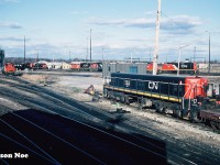 While touring around CN’s MacMillan yard diesel shop one November afternoon we stopped to photograph M-420(W) 3507, which had just emerged from one of the bays.  A young hostler helper was busy closing engine compartment doors and doing some other inspections, when he spotted us below. “Hey, you guys wanna come up for a ride?” he asked.  Well, that question was answered quickly as we all piled into 3507’s warm cab. It wasn’t a long trip, as it was just to put the unit over onto another shop track. However, seeing the shop from onboard a unit was something I’ll never forget, especially from the cab of an M-420(W).
<br>
Here, GP9 Slug 253 is seen during our cab ride with a sea of other various CN motive power crowding the diesel shop tracks including GP9RM’s 7081 and 7082, plus a transfer caboose. 
